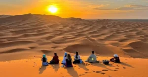 Viajantes observando o pôr do sol nas dunas do Saara